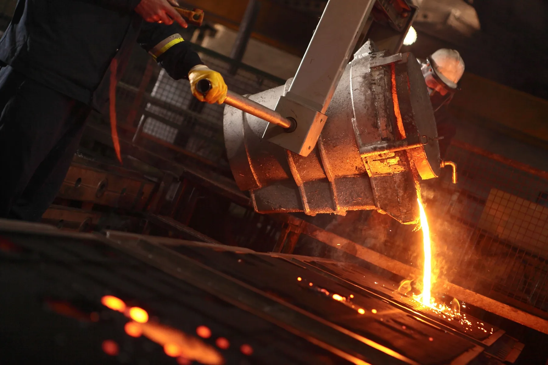 Molten iron pouring from a ladle into a mould on the foundry floor